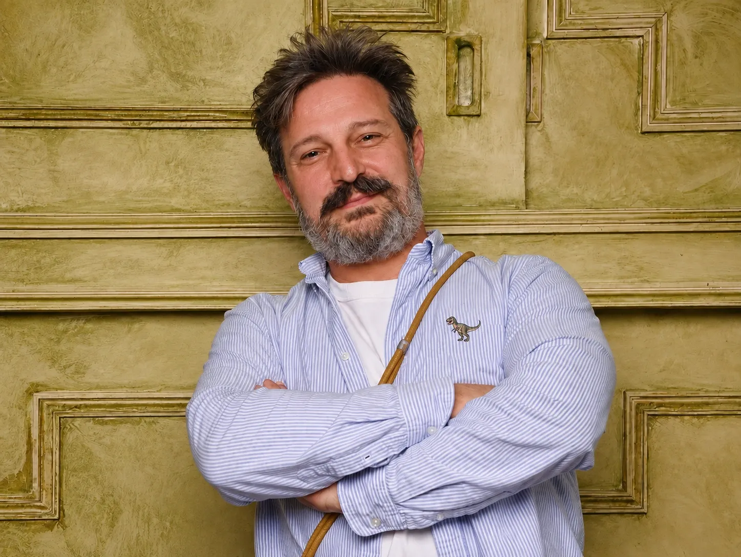 Baptiste de Prailles, bras croisés, devant une porte ancienne.